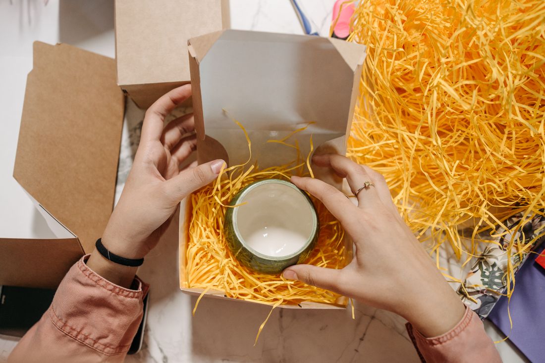 Manos colocando una taza de cerámica en una caja con material protector; imagen ilustrativa
