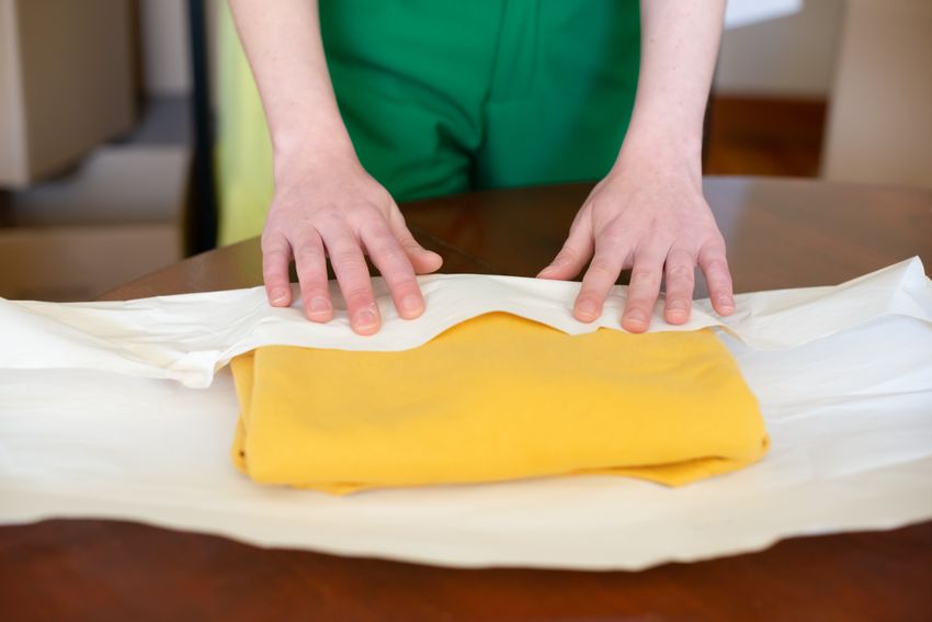Una persona envuelve prendas de ropa para preparar pedidos