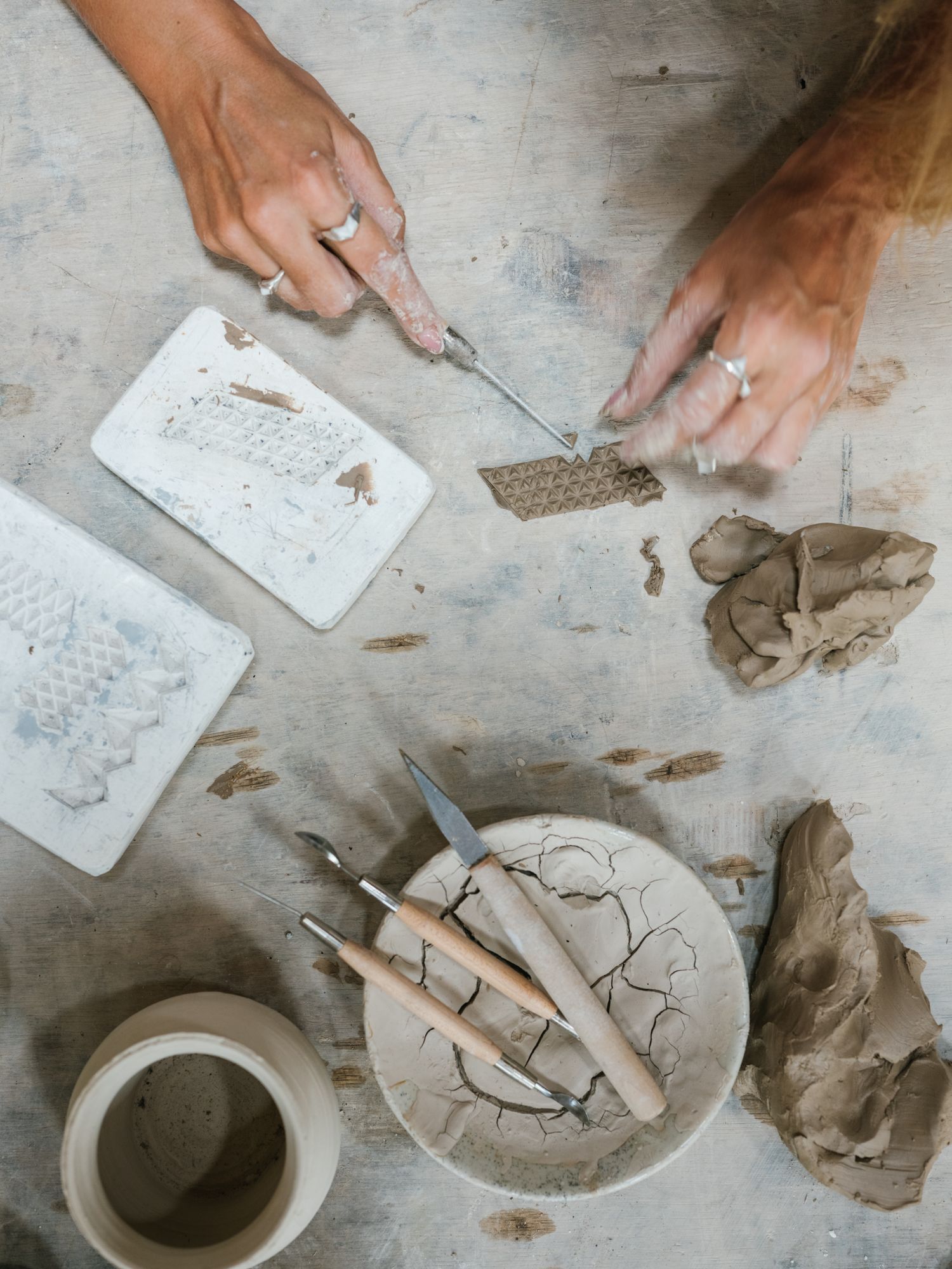 Manos de una artesana trabajando cerámica en una mesa de taller